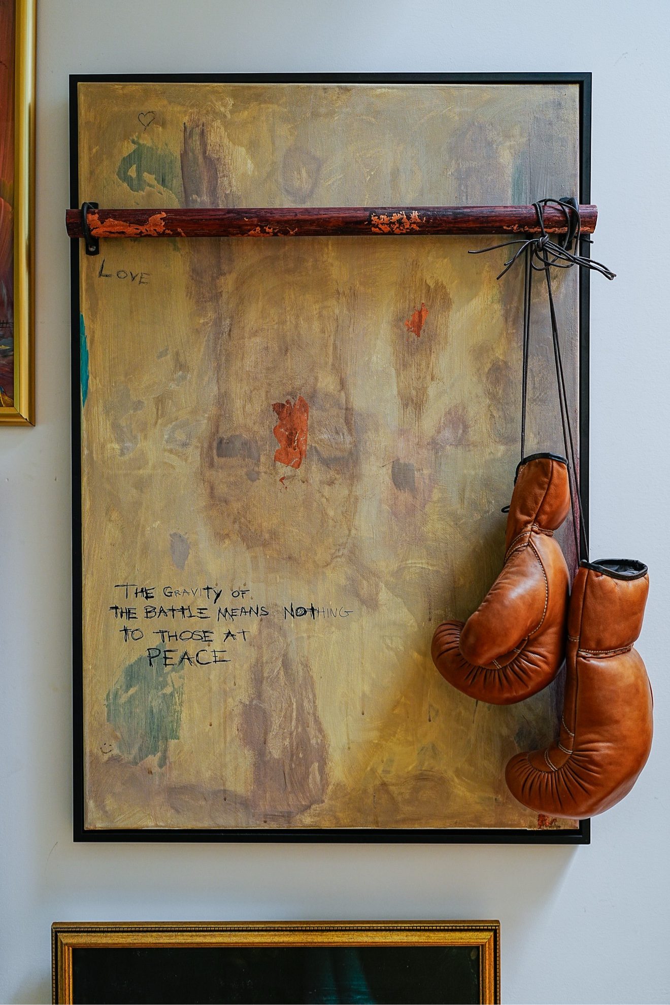 Gallery wall with boxing-glove artwork reading 'The gravity of the battle'