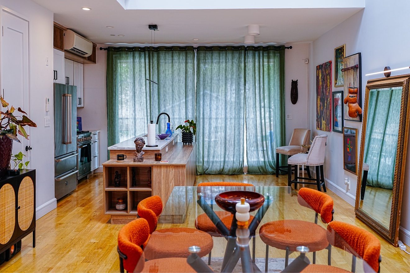 Chef's-style kitchen with green curtains, island seating, and warm daylight