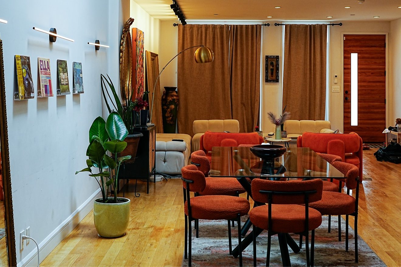 Open living area with orange armchairs, glass coffee table, and tall windows