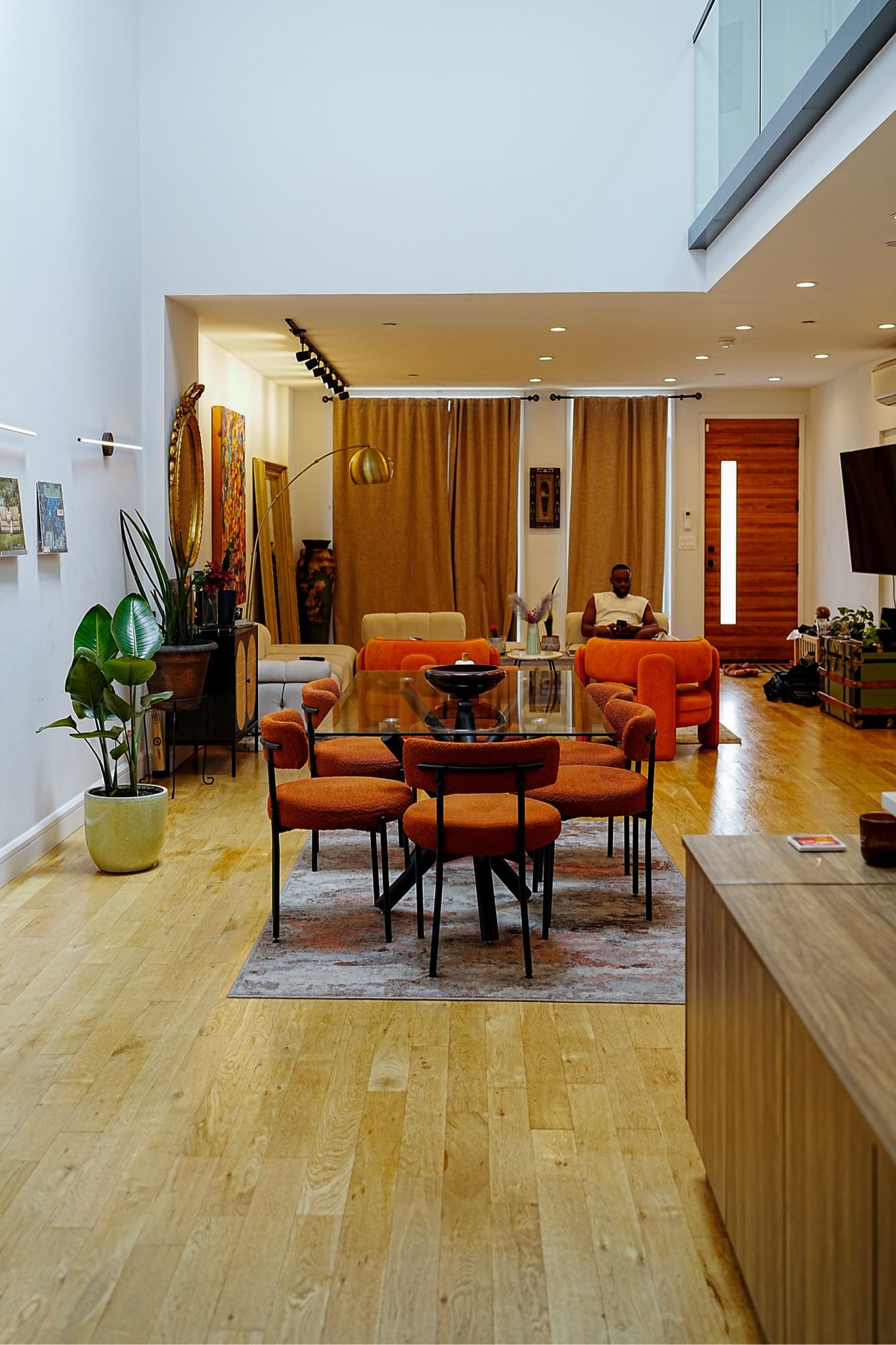 Double-height living space with mezzanine, tall windows, and sculptural furniture